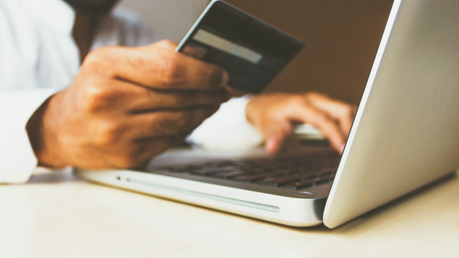 Customer using a payment card beside a laptop during an online subscription payment